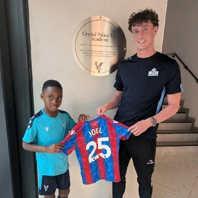 Dominic Timms presenting a football shirt with a young player